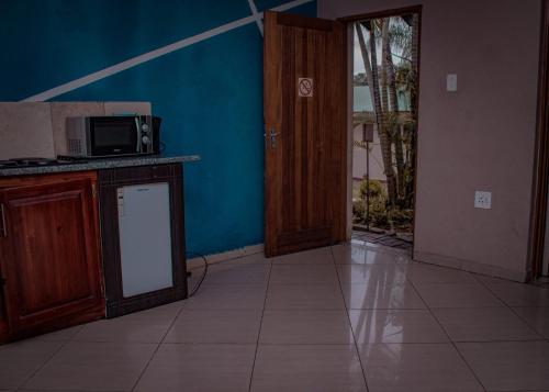 a room with a kitchen with a microwave and a door at Nomanini guest house Nelspruit in Nelspruit