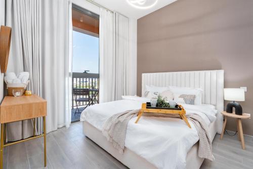 a white bedroom with a bed and a balcony at Tamm - Noor 2 Tower in Dubai