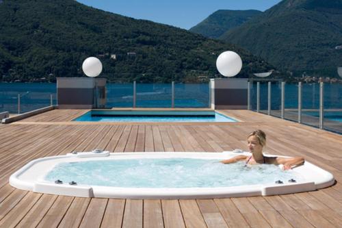 een vrouw in een bubbelbad op een dek bij Vista di Maccagno Fantastico Pool in Maccagno Superiore