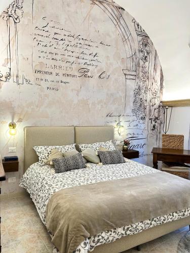 ein Schlafzimmer mit einem Bett mit einer Wand mit einem Schreibtisch in der Unterkunft Ex Monastero Pieno Centro storico in Bitetto