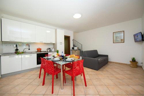 cocina y sala de estar con mesa y sillas rojas. en Le Betulle Garden in Laveno, en Laveno-Mombello