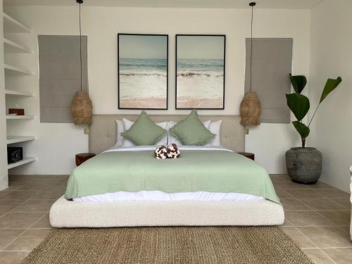 a bedroom with a green bed with three pictures of the beach at New!2BR,400M to the Beach Cemagi in Tanah Lot