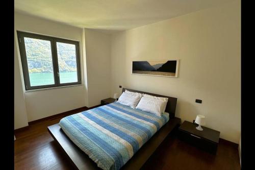 1 dormitorio con 1 cama con edredón azul y 2 ventanas en Riflessi sul lago apt – Laglio en Laglio