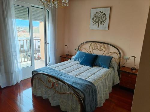 een slaapkamer met een bed met blauwe kussens en een raam bij La Casa de Ana in El Barco de Ávila