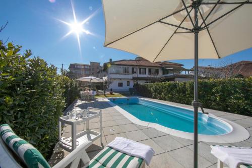 ein Pool mit einem Sonnenschirm, einigen Stühlen und einem Tisch in der Unterkunft Casa Amabile With Pool in Reno Di Leggiuno