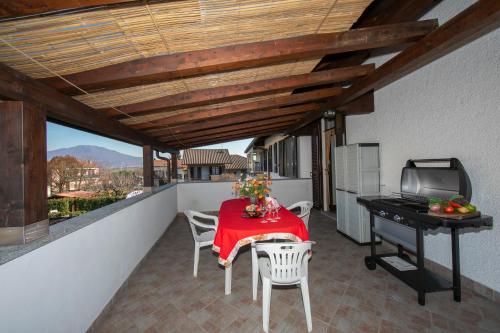 einen Balkon mit einem Tisch, Stühlen und einem Grill in der Unterkunft Casa Amabile With Pool in Reno Di Leggiuno