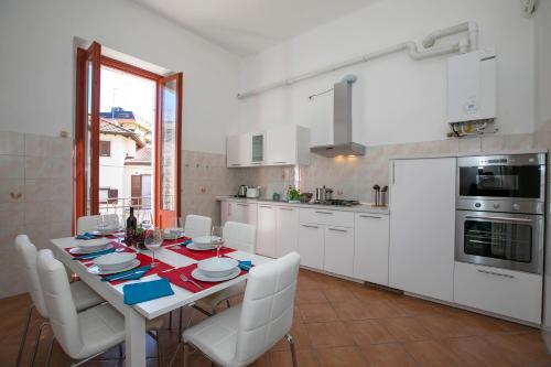 a kitchen with a table with white chairs and a kitchen with white appliances at Residenza Gardenia Lake View Luino Center - Happy Rentals in Luino