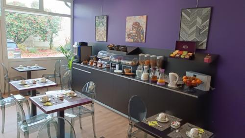 a restaurant with two tables and a purple wall at Hôtel Le Rohan Charme et Caractère in Pontivy