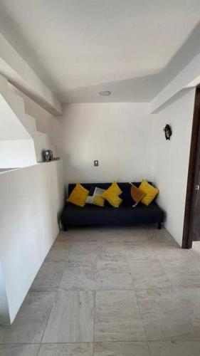 a room with a black couch with yellow pillows at Bonita casa nueva con alberca climatizada y aire acondicionado en Oaxtepec Morelos in Oaxtepec