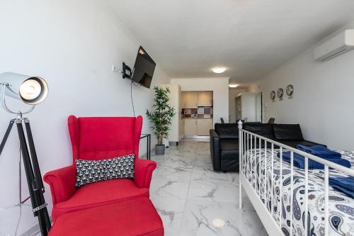 a living room with a red chair and a bed at T0 Vilamoura Downtown in Vilamoura