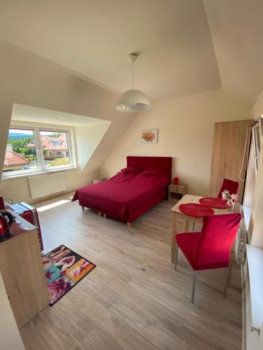 1 dormitorio con cama roja y mesa en Słoneczne Apartamenty Polanica-Zdrój en Polanica-Zdrój