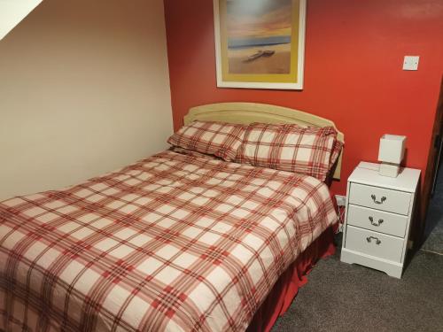 ein Schlafzimmer mit einem Bett mit einer karierten Decke und einem Nachttisch in der Unterkunft Aughnahoy Staycations Portglenone in Portglenone