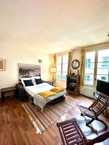a bedroom with a bed and a table and windows at Cozy 1BR in the Heart Of Paris in Paris