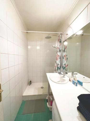 La salle de bains blanche est pourvue d'un lavabo et d'une baignoire. dans l'établissement Cozy 1BR in the Heart Of Paris, à Paris