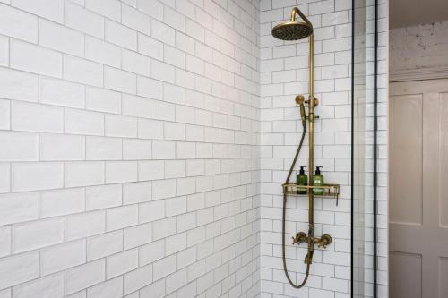 a shower with white tiled walls and a shower head at Seaside Hideout - close to beach in Eastbourne