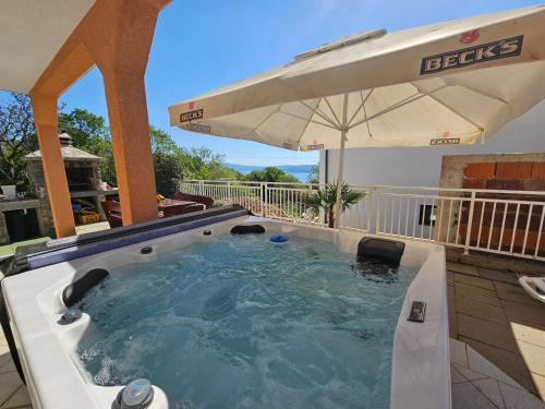 a hot tub with an umbrella in a backyard at Apartments Lujić in Crikvenica