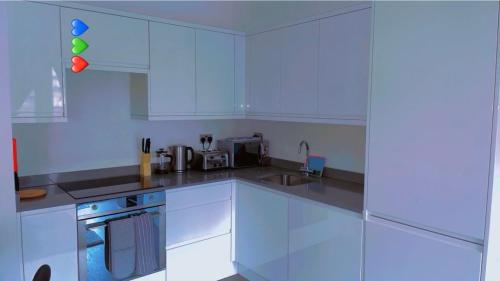 a white kitchen with a sink and a stove at Absolute Stays at The Ridgmont-St Albans-High Street- Near Luton Airport - St Albans Abbey Train station -Close to London- Harry Potter World - The Odyssey Cinema-Contractors -London Road-Business-Leisure in St. Albans