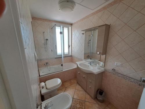 e bagno con lavandino, servizi igienici e vasca. di ALICE B&B a Villasimius