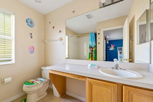 a bathroom with a sink and a toilet and a mirror at Resort w Lazy River and Arcade 30mis to Disney in Davenport