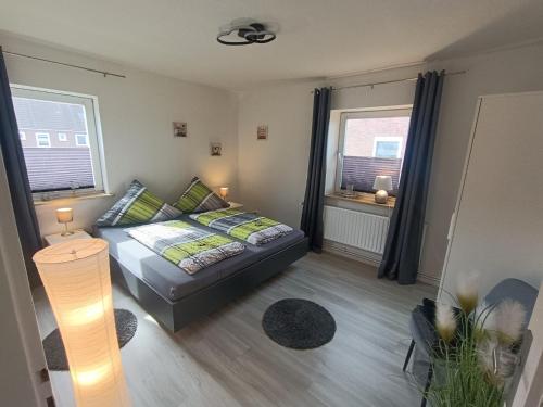 ein kleines Schlafzimmer mit einem Bett und zwei Fenstern in der Unterkunft Küstenliebe in Wilhelmshaven