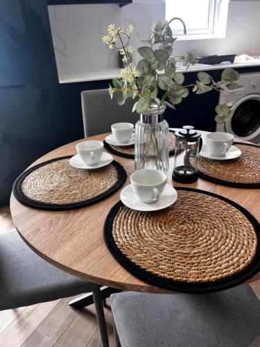 Seaside Serenity في ليانيلي: طاولة خشبية مع صحون واكواب و مزهرية بها ورد