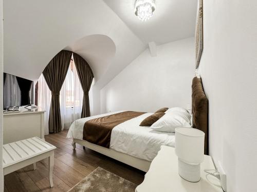 a white bedroom with a bed and a window at Complex Vila Rania in Satu Mare