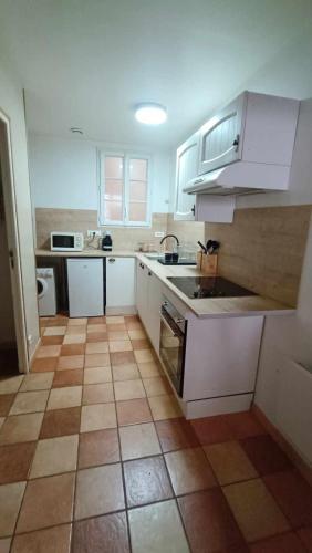 une cuisine avec des armoires blanches et un sol carrelé dans l'établissement Terre de Bourgogne - Appartement au centre ville d'Avallon, à Avallon