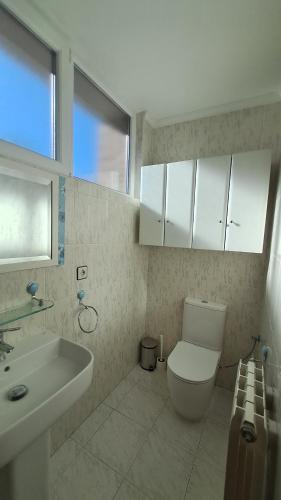 a bathroom with a white toilet and a sink at Casa grande con jardín in Santa Cruz de Bezana