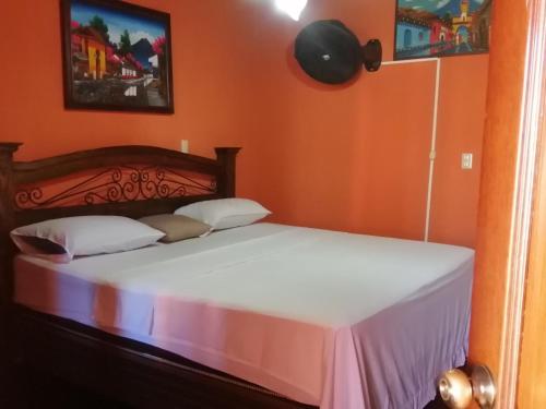 Bett in einem Zimmer mit orangefarbener Wand in der Unterkunft Hotel city of antigua s.a in Antigua Guatemala