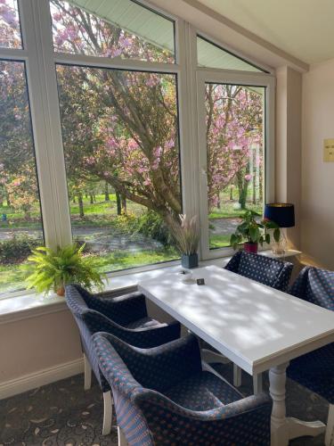 une table et des chaises dans une pièce avec fenêtres dans l'établissement Fernhill Lodge Carrigaline, à Cork