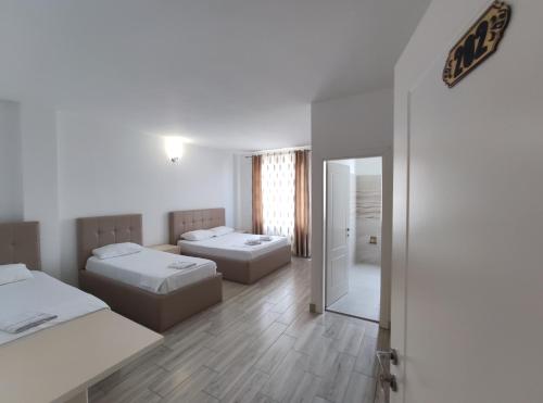 Habitación blanca con 2 camas y espejo. en Hotel Restaurant Univers en Shkodër