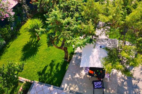 een uitzicht op een tuin met een wit huis en bomen bij Platamoon Garden - with enchanting garden in Platamona