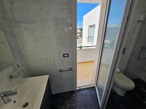 uma casa de banho com um chuveiro, um lavatório e um WC. em Infinity Residence con Parcheggio em Porto Cesareo