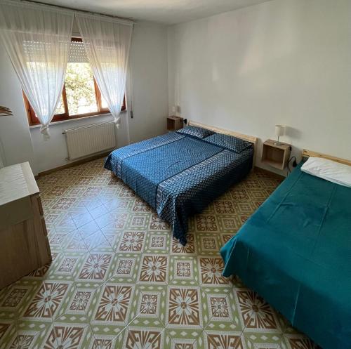 sypialnia z dwoma łóżkami i kafelkową podłogą w obiekcie Casa Palma - 300mt dal Mare w mieście Marina di Massa