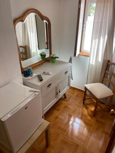 a bathroom with a dresser with a mirror and a chair at Pensão Dona Ana in Lagos