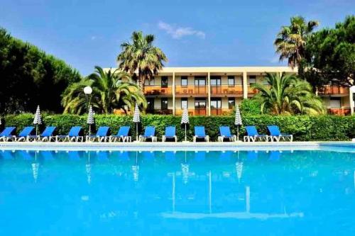 un complexe avec une piscine entourée de chaises et un bâtiment dans l'établissement Mandelieu / Appart Climatisé 4 prsn RDC / Piscine, à Mandelieu-la-Napoule