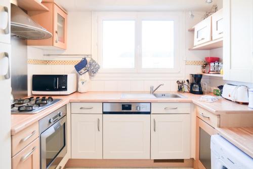 a kitchen with white cabinets and a sink and a window at Appartement spacieux idéalement situé sur le remblai des Sables dOlonne in Les Sables-dʼOlonne