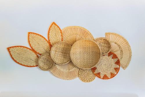 a straw hat with a flower on a white background at Casa Dela Pousada in Cabo Frio