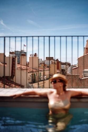 a woman in a swimming pool with a city in the background at Grand Hôtel Dauphiné Toulon, Boutique Hôtel & Suites in Toulon
