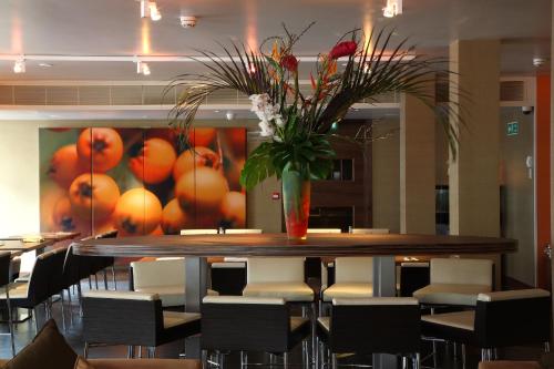 a dining room table with chairs and a vase of flowers at Hotel Bosco in Kingston upon Thames