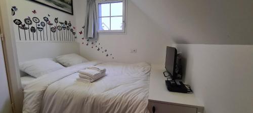 une chambre avec un lit avec des draps blancs et une télévision dans l'établissement Le cottage sauvage, à Équihen-Plage