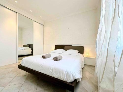 une chambre avec un grand lit blanc et un miroir dans l'établissement Le Biggi : Apt 3 Prs, jardin, 5 min plages, à Vallauris