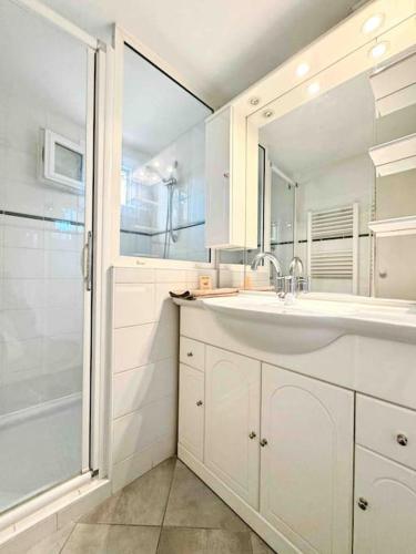 une salle de bain blanche avec un lavabo et une douche dans l'établissement Le Biggi : Apt 3 Prs, jardin, 5 min plages, à Vallauris