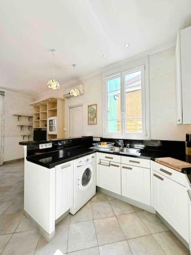 une cuisine avec des armoires blanches et une machine à laver dans l'établissement Le Biggi : Apt 3 Prs, jardin, 5 min plages, à Vallauris