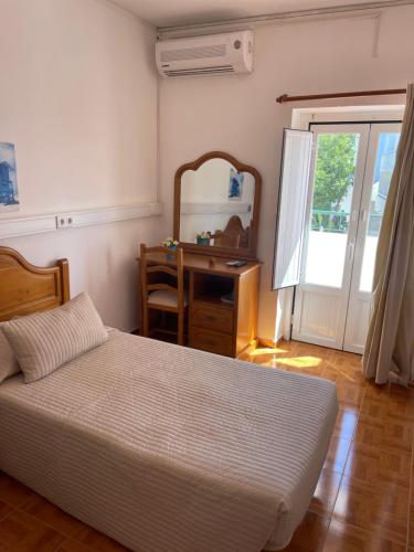a bedroom with a bed and a desk and a mirror at Pensão Dona Ana in Lagos