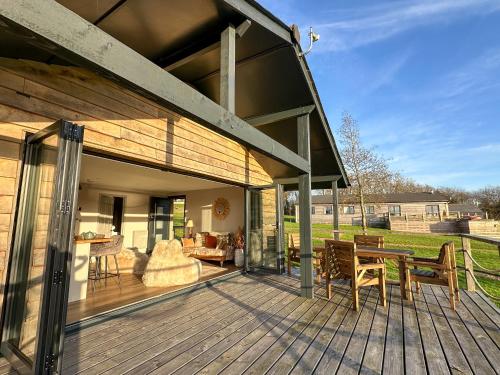 una terraza de madera con sillas y mesa en Zen Jungle Retreat - Log Cabin Stays, Transformational Retreats & Holistic Wellness near Bude - A 40 Acre Retreat with 5 Lakes, Woodland, Firepits, Bistro & Bars, en Holsworthy