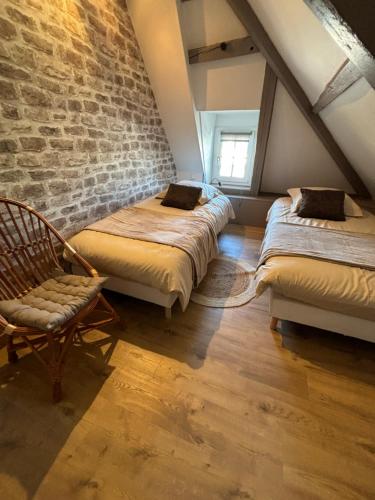 Cette chambre mansardée comprend 3 lits et une chaise. dans l'établissement LE QG, à Sainte-Mère-Église
