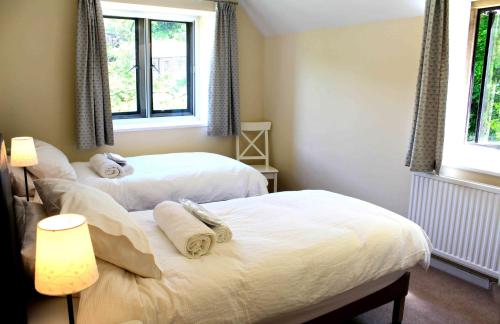 two beds in a bedroom with two windows at Springfield Coach House - Leisure and Business travellers in Stroud