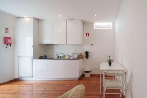 - une cuisine avec des placards blancs et une table dans une pièce dans l'établissement Home Mais Sant’Ana, à Lisbonne