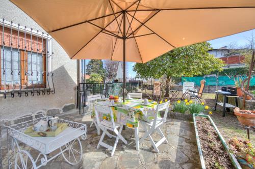 ein Tisch und Stühle unter einem Sonnenschirm auf einer Terrasse in der Unterkunft La Finestra Sul Lago - Happy Rentals in Stresa